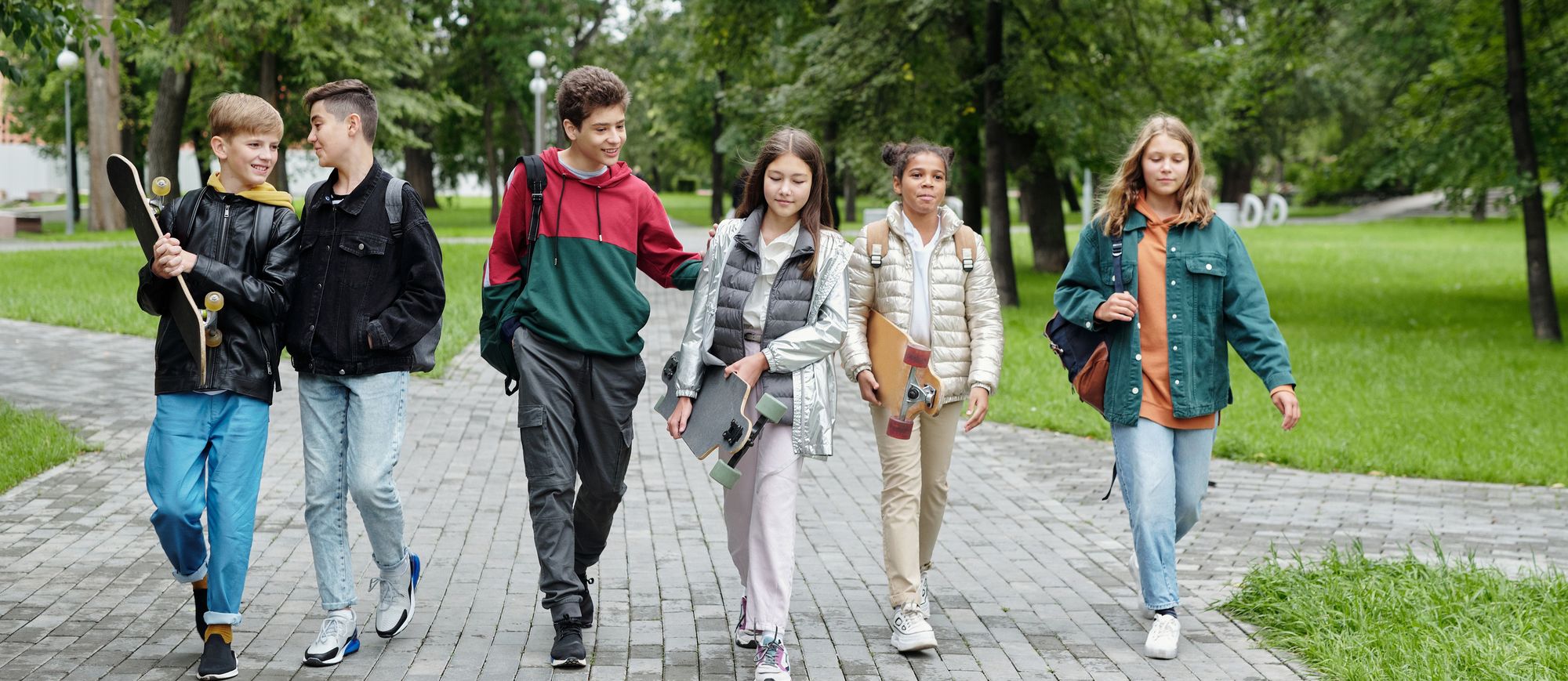 A group of pre-teens and teenagers walking together through a park