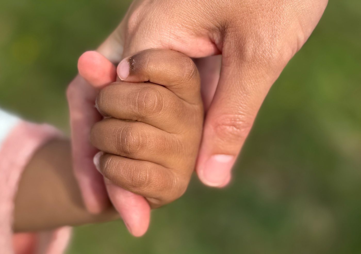 An adult's hand gently holding a child's hand